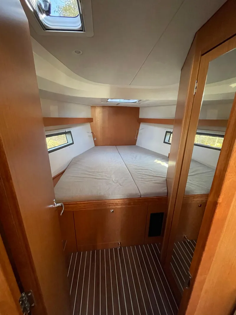 Slide: The Image of 2023 Bavaria C42 yacht cabin with cozy bed, wooden interior, and natural light. - 15