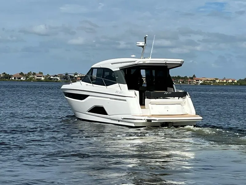 Slide: The Image of 2023 Bavaria R40 Coupe cruising on a serene lake under a partly cloudy sky. - 2