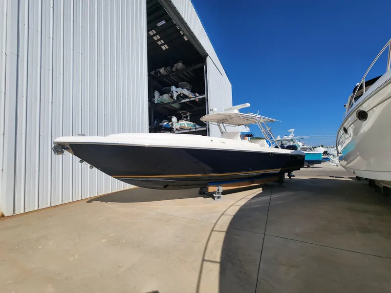 The Image of 2008 Intrepid 323 Cuddy boat docked outside a large storage facility under clear blue skies. - 0