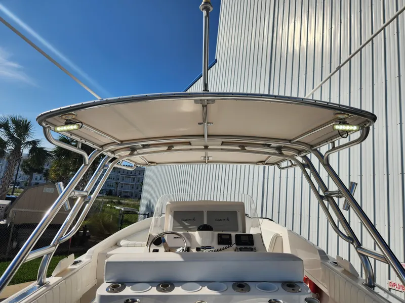 Slide: The Image of 2008 Intrepid 323 Cuddy boat with T-top and modern navigation equipment, docked near a building. - 23