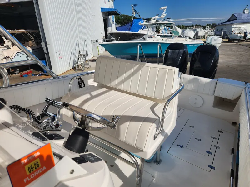 Slide: The Image of 2008 Intrepid 323 Cuddy boat interior with white seating and steering wheel, docked in Florida. - 28