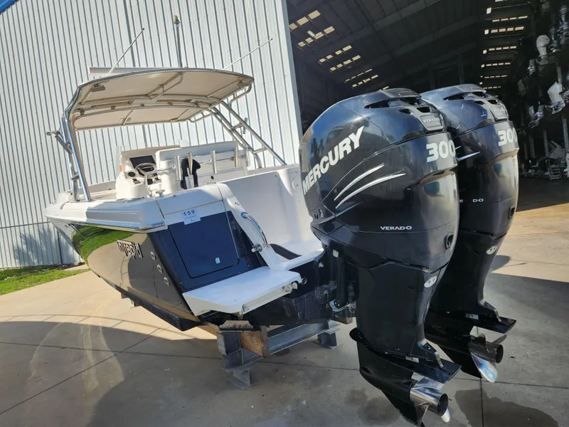 Slide: The Image of 2008 Intrepid 323 Cuddy with dual Mercury 300 Verado engines, docked near a large warehouse. - 5