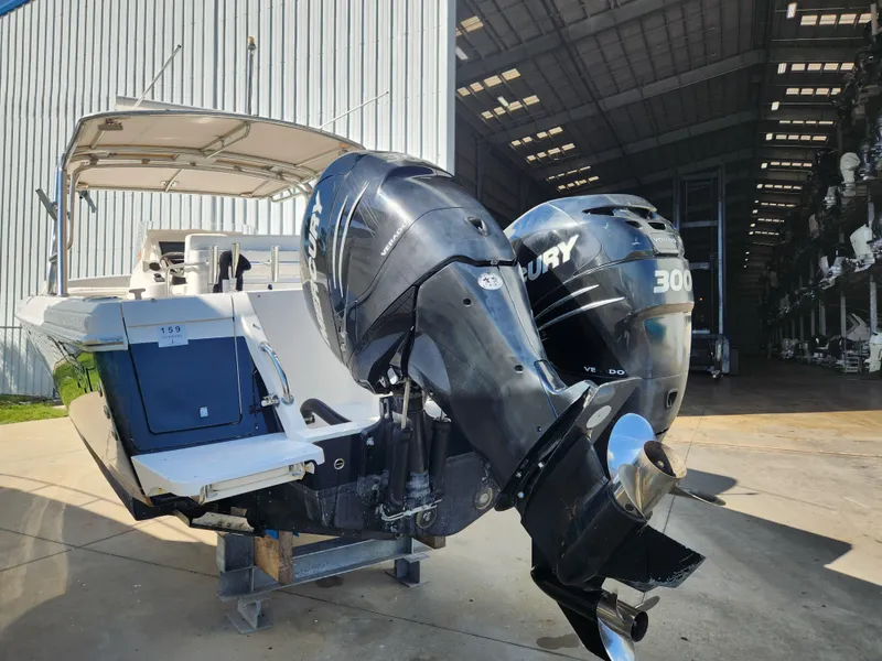 Slide: The Image of 2008 Intrepid 323 Cuddy with dual Mercury 300 engines, docked near a large storage facility. - 7