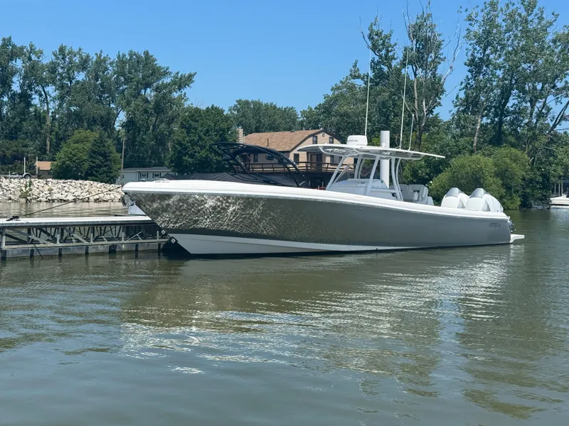 The Image of 2018 Intrepid 375 Open boat docked on a calm river, surrounded by trees. - 0