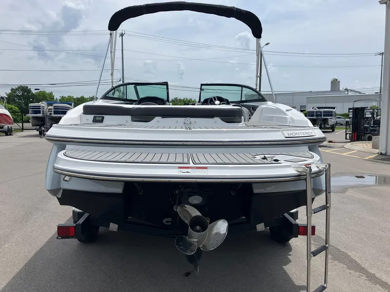 Slide: The Image of 2022 Monterey 224FS boat rear view with swim platform and ladder in a marina. - 2
