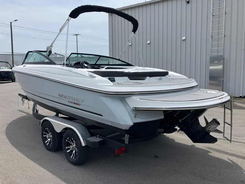 Slide: The Image of 2022 Monterey 224FS boat on trailer, parked outdoors near a metal building. - 3