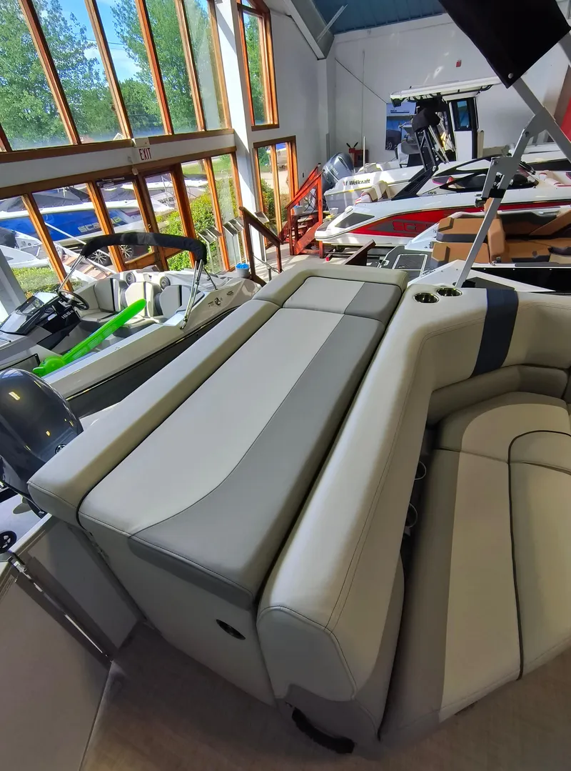 Slide: The Image of 2025 SunCatcher Select 18C boat interior with plush seating in a showroom. - 10