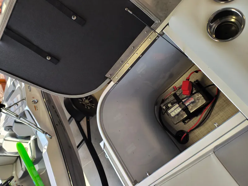 Slide: The Image of Open storage compartment in 2025 SunCatcher Select 18C boat, revealing battery setup. - 13