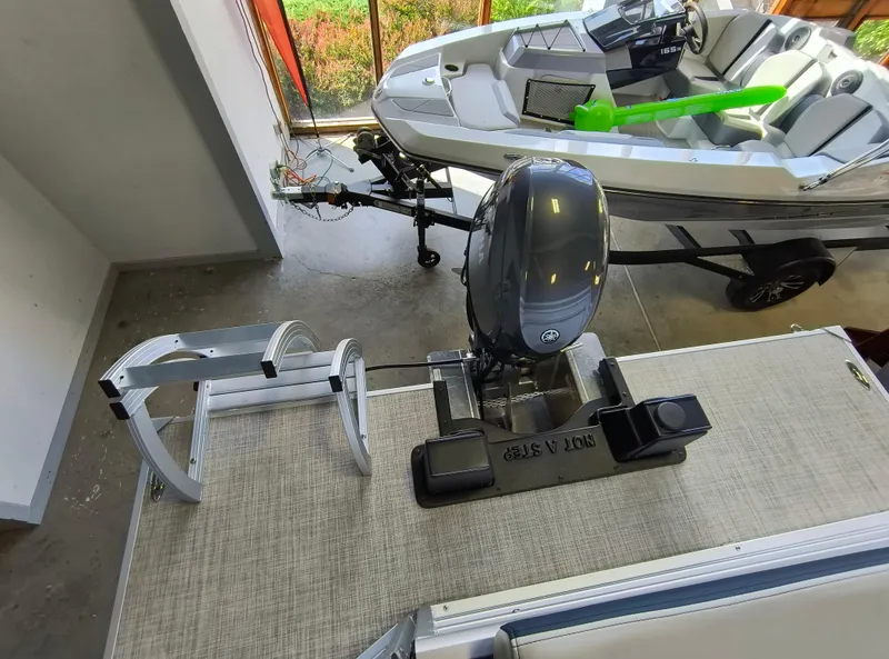 Slide: The Image of 2025 SunCatcher Select 18C boat with motor and ladder in a showroom. - 14