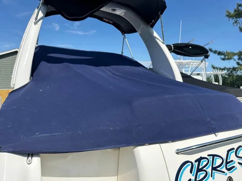Slide: The Image of 2006 Sea Ray 260DA boat with blue cover, docked under clear sky. - 11