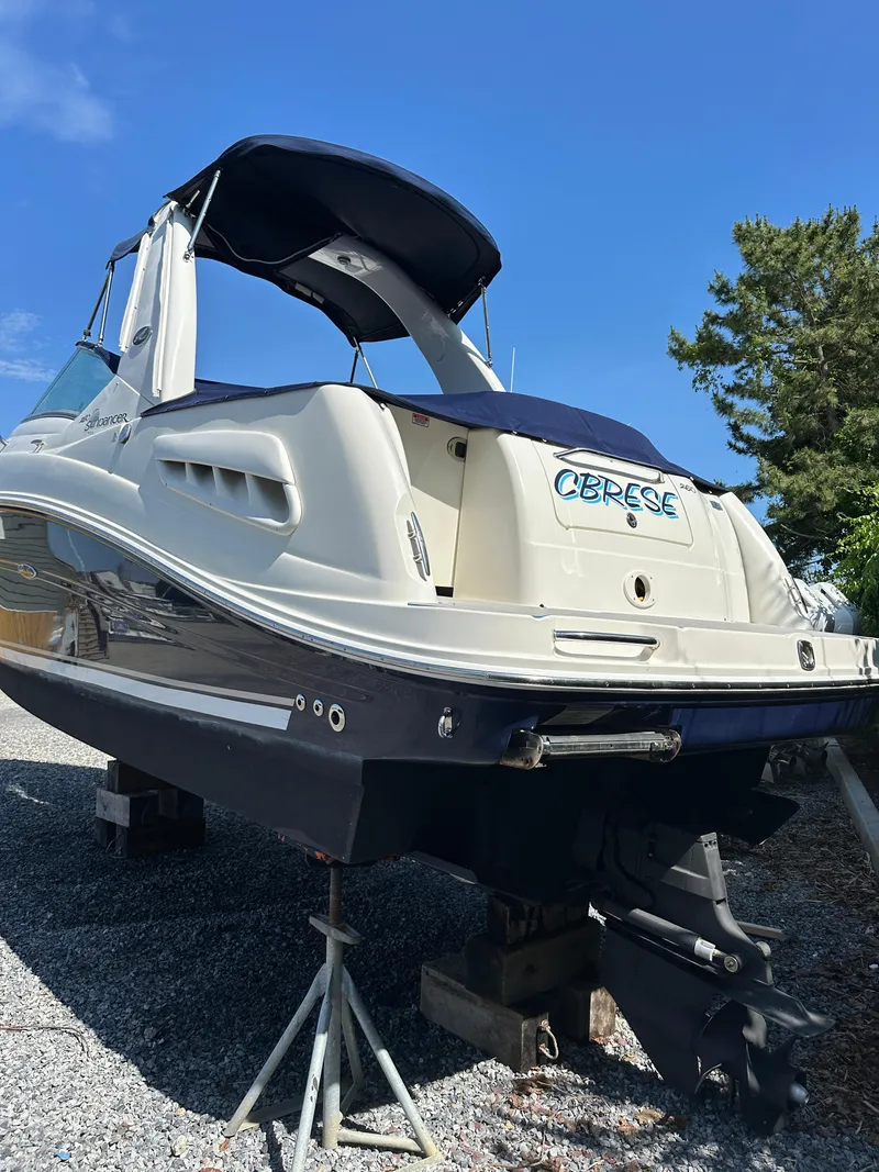 Slide: The Image of 2006 Sea Ray 260DA boat on stands, blue and white, under clear sky. - 2