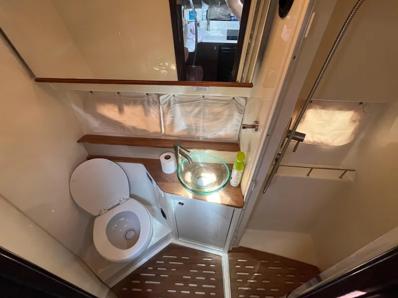 Slide: The Image of 2018 Sea Ray Sundancer 350 bathroom with toilet, glass sink, and wooden accents. - 27
