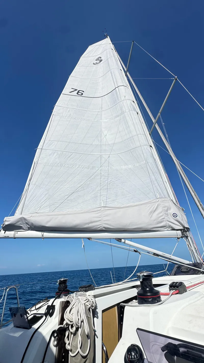 Slide: The Image of 2023 Beneteau Oceanis 34.1 sailboat with raised sails against a clear blue sky. - 12