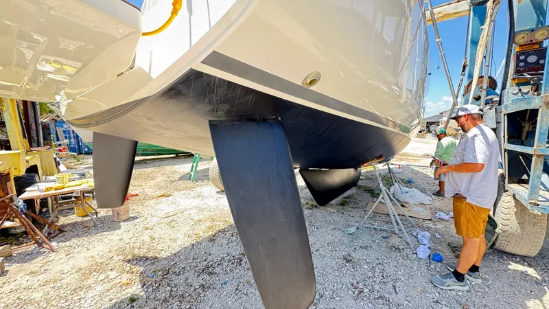Slide: The Image of 2023 Beneteau Oceanis 34.1 sailboat in dry dock, with a person inspecting the hull. - 13