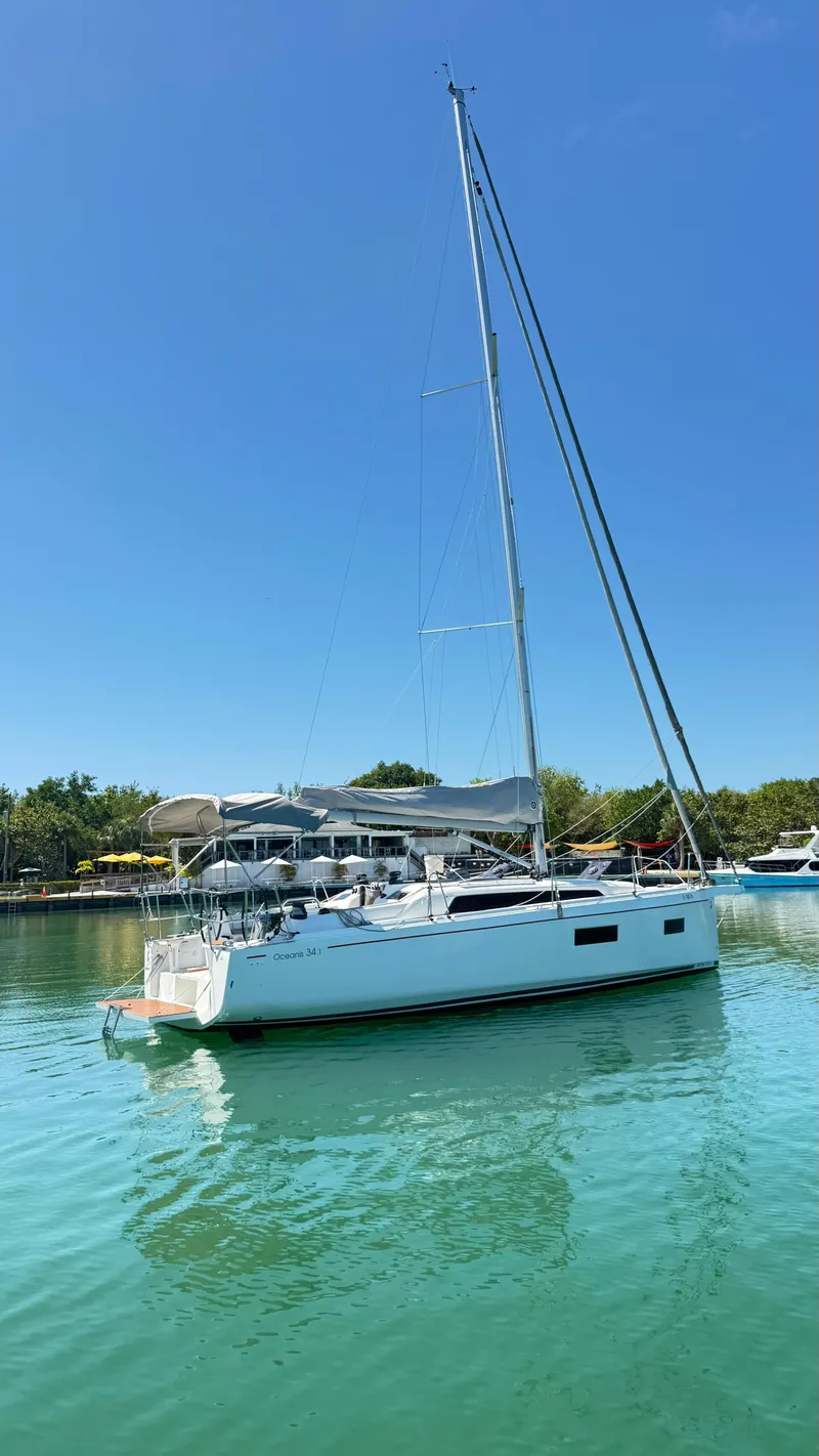 Slide: The Image of 2023 Beneteau Oceanis 34.1 sailboat on calm water under clear blue sky. - 2