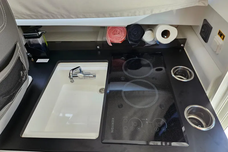 Slide: The Image of 2023 Jeanneau NC795 S2 kitchen with sink, stove, and storage. - 18