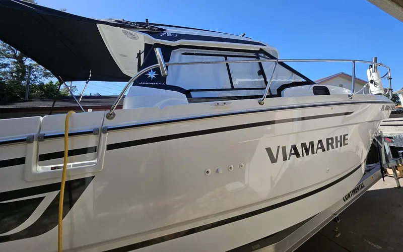 Slide: The Image of 2023 Jeanneau NC795 S2 boat with "VIAMARHE" on the side, docked outdoors. - 2