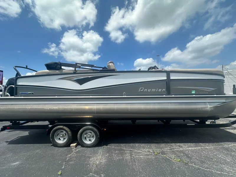 Slide: The Image of 2023 Premier 250 Solaris pontoon boat on trailer under a blue sky with clouds. - 2