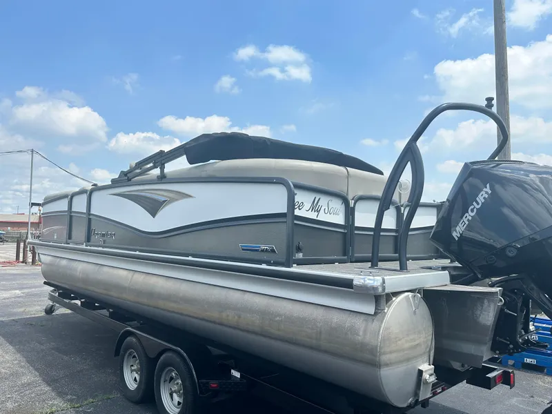 Slide: The Image of 2023 Premier 250 Solaris pontoon boat with Mercury engine on trailer under blue sky. - 4