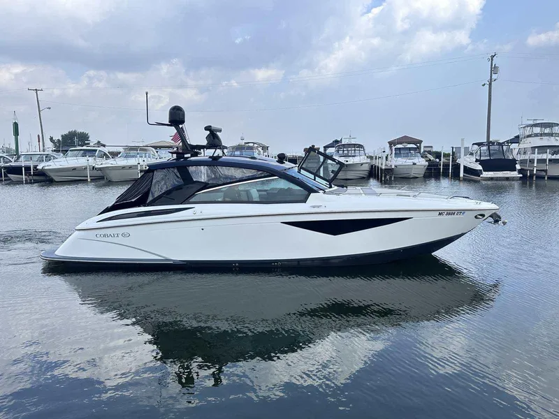 The Image of 2019 Cobalt A36 boat docked in a marina, surrounded by other vessels. - 0
