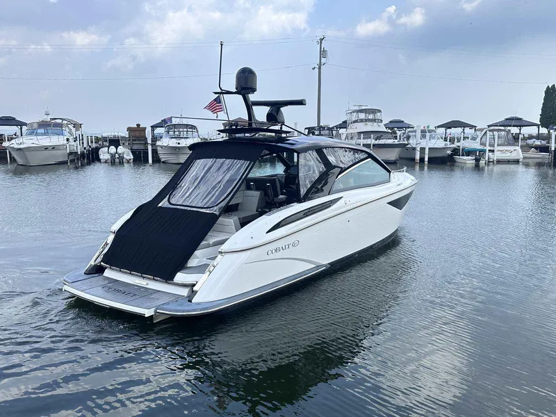 Slide: The Image of 2019 Cobalt A36 boat docked in marina, surrounded by other boats under cloudy sky. - 2