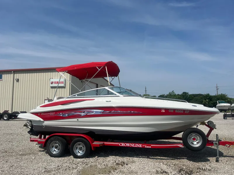 The Image of 2007 Crownline 220 EX boat with red canopy on trailer, parked outdoors. - 0