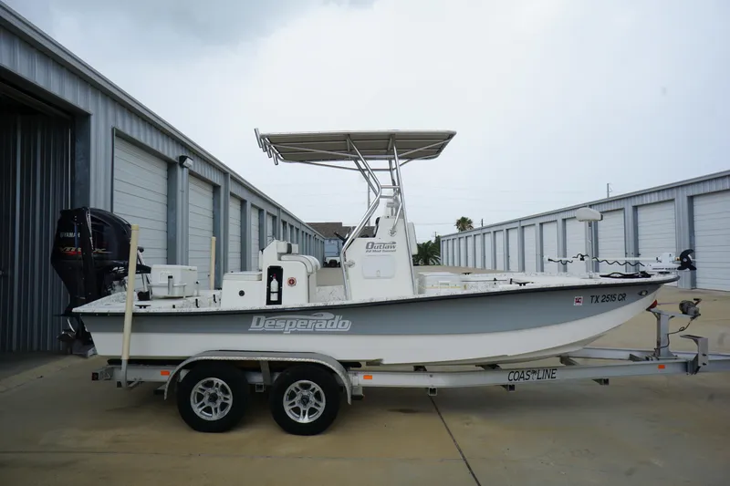 Slide: The Image of 2015 Desperado 22 Outlaw boat on trailer near storage units. - 0