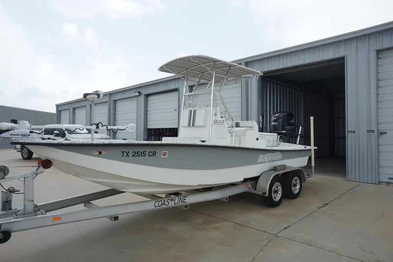 Slide: The Image of 2015 Desperado 22 Outlaw boat on trailer near storage units. - 2