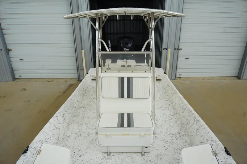 Slide: The Image of 2015 Desperado 22 Outlaw boat with T-top and dual seating, parked near storage units. - 6