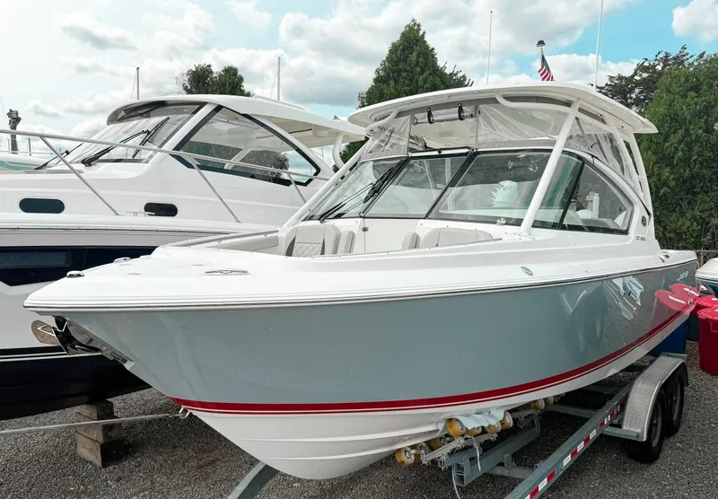 The Image of 2025 Pursuit DC 266 Dual Console boat on trailer, parked outdoors. - 0