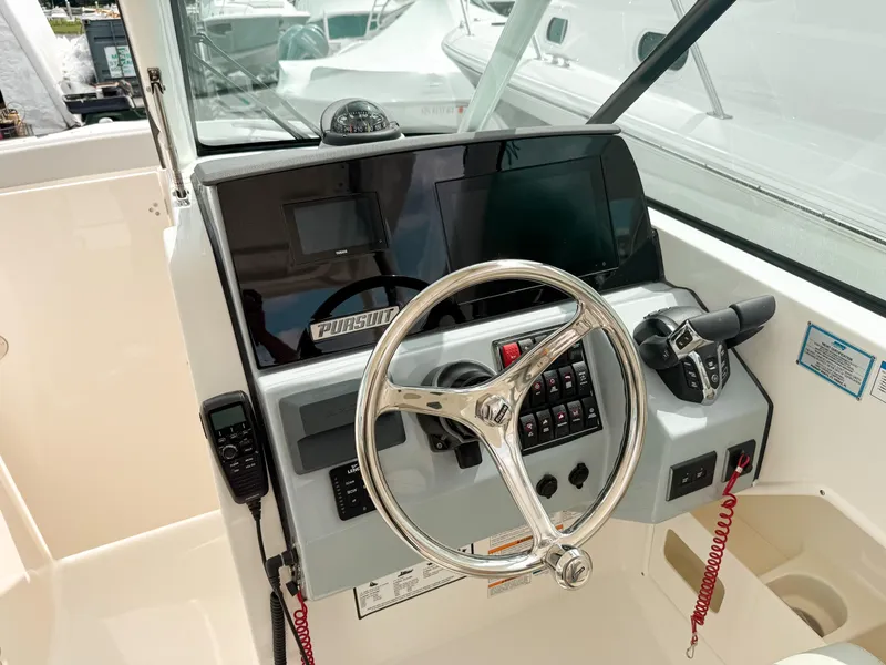 Slide: The Image of 2025 Pursuit DC 266 Dual Console boat helm with steering wheel and control panel. - 12