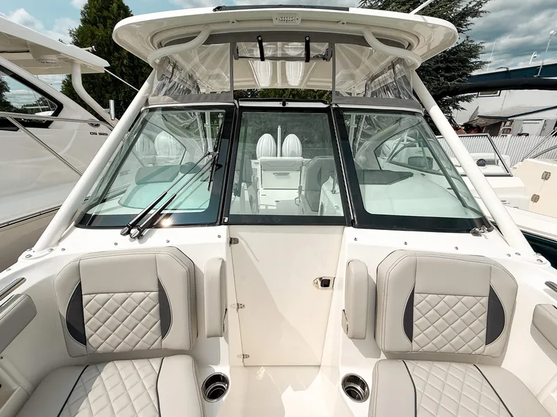 Slide: The Image of 2025 Pursuit DC 266 Dual Console boat interior with cushioned seating and windshield. - 17