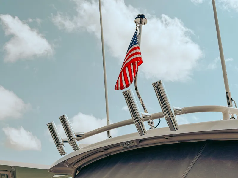 Slide: The Image of 2025 Pursuit DC 266 Dual Console boat with American flag against blue sky. - 2