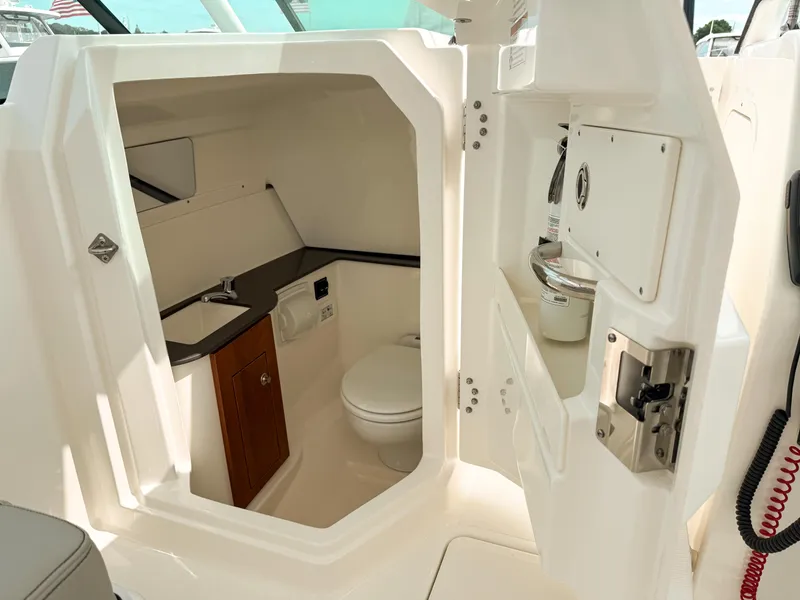 Slide: The Image of 2025 Pursuit DC 266 Dual Console boat interior with compact bathroom and sink. - 20