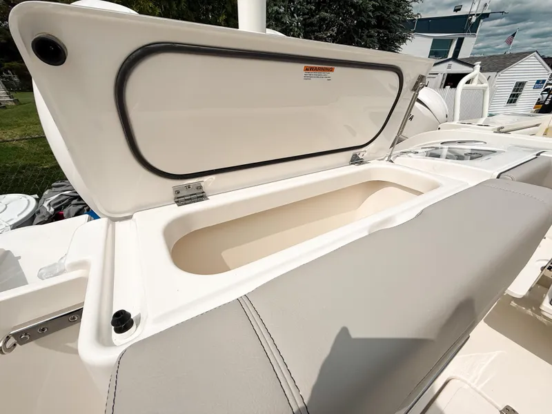 Slide: The Image of 2025 Pursuit DC 266 Dual Console boat storage compartment open, showcasing interior space. - 23
