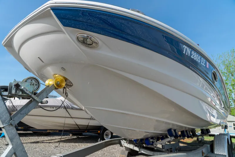 Slide: The Image of 2012 Crownline Eclipse E2 boat on trailer, blue and white hull, sunny day. - 3