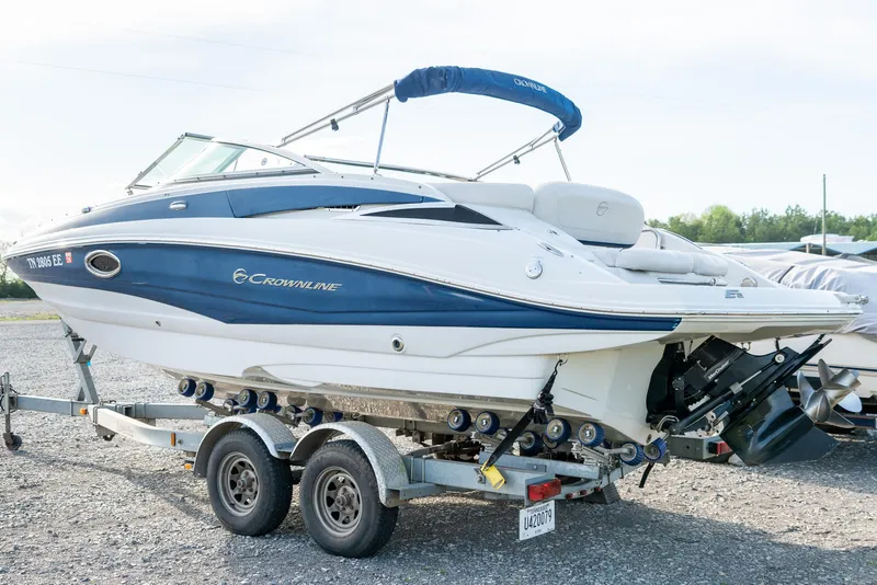 Slide: The Image of 2012 Crownline Eclipse E2 boat on trailer, blue and white design, parked outdoors. - 6
