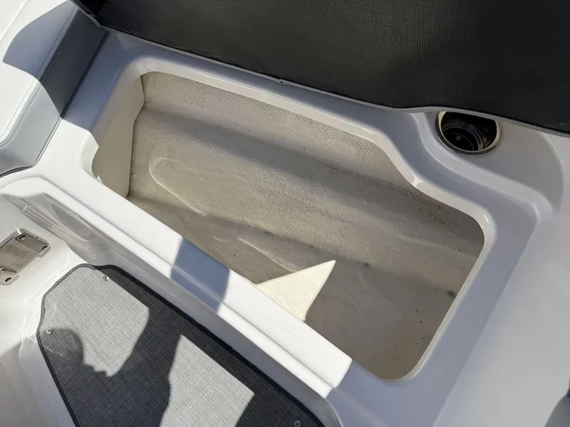Slide: The Image of Open storage compartment in 2022 Chaparral 23 SSi boat, featuring white interior and gray flooring. - 10
