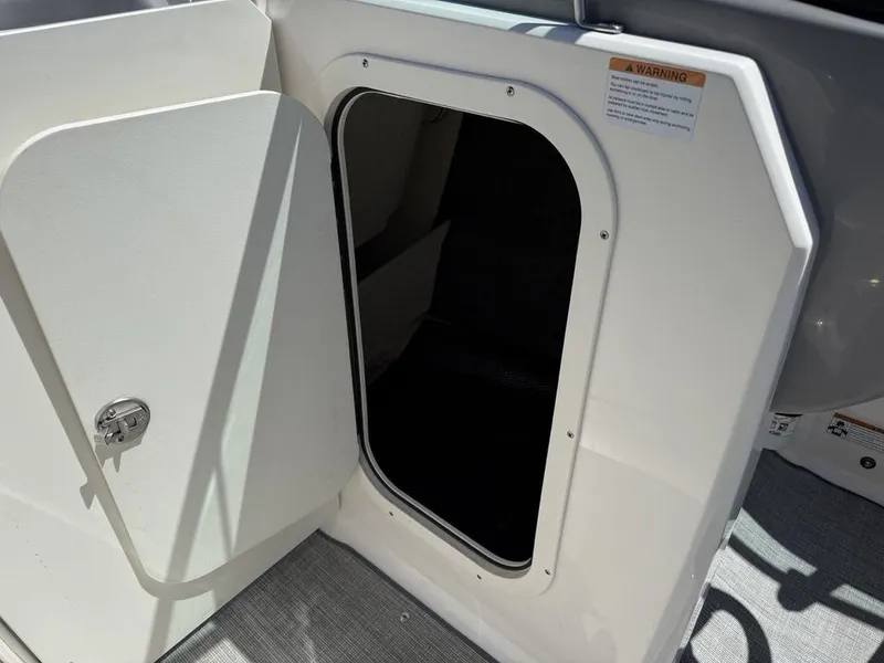Slide: The Image of 2022 Chaparral 23 SSi boat storage compartment with open door and warning label. - 13