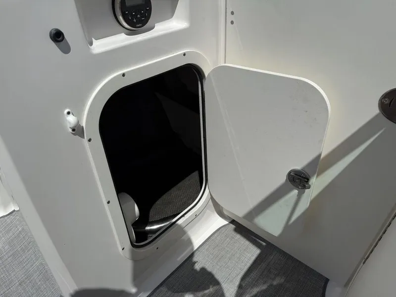 Slide: The Image of Open storage compartment on 2022 Chaparral 23 SSi boat, featuring a white interior. - 16