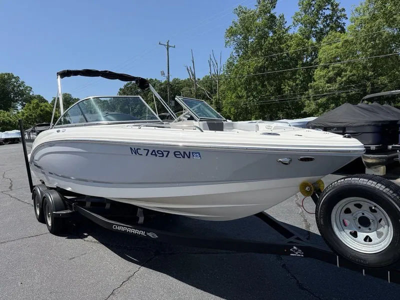 Slide: The Image of 2022 Chaparral 23 SSi boat on trailer, parked outdoors, surrounded by trees. - 5