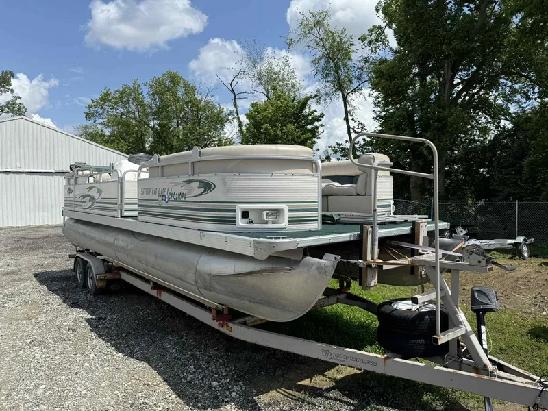 The Image of 1999 Smoker Craft 8526 Pleasure Isle I/O pontoon boat on trailer, parked outdoors. - 0