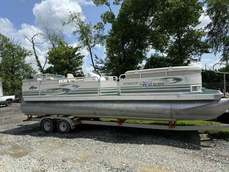 Slide: The Image of 1999 Smoker Craft 8526 Pleasure Isle I/O pontoon boat on trailer, parked outdoors. - 1