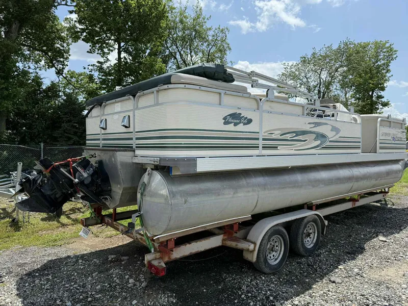 Slide: The Image of 1999 Smoker Craft 8526 Pleasure Isle I/O pontoon boat on trailer, parked outdoors. - 2
