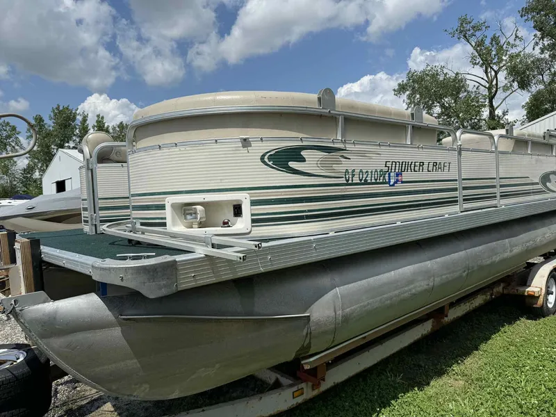 Slide: The Image of 1999 Smoker Craft 8526 Pleasure Isle I/O pontoon boat on trailer, under a blue sky. - 5