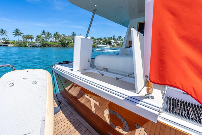 Slide: The Image of 2018 Grand Banks GB60 yacht with red flag, docked near tropical shoreline. - 10