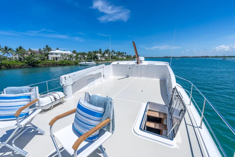 Slide: The Image of Luxurious 2018 Grand Banks GB60 yacht deck with chairs, overlooking serene blue waters and coastal homes. - 22