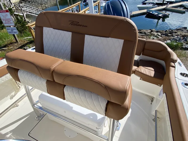 Slide: The Image of 2025 Pioneer 202 Islander boat interior with brown and white seating, docked at a marina. - 7