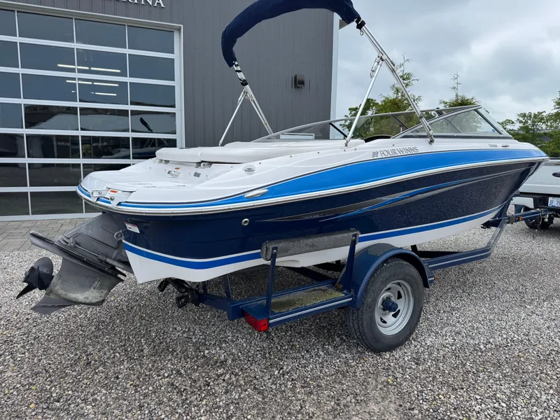 Slide: The Image of 2008 Four Winns H200 boat on trailer, blue and white, parked on gravel. - 3