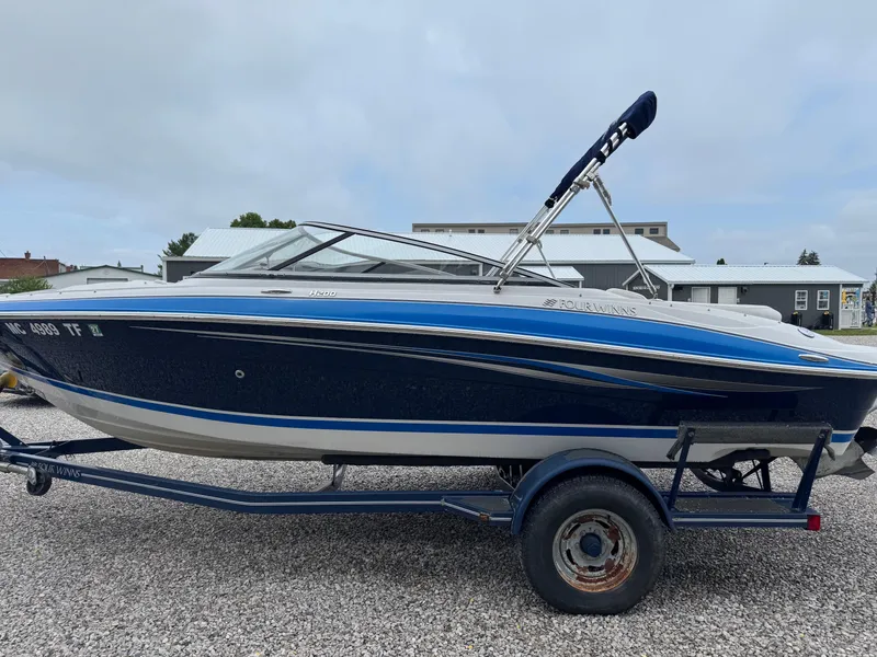 Slide: The Image of 2008 Four Winns H200 boat on trailer, blue and white design, parked on gravel. - 6